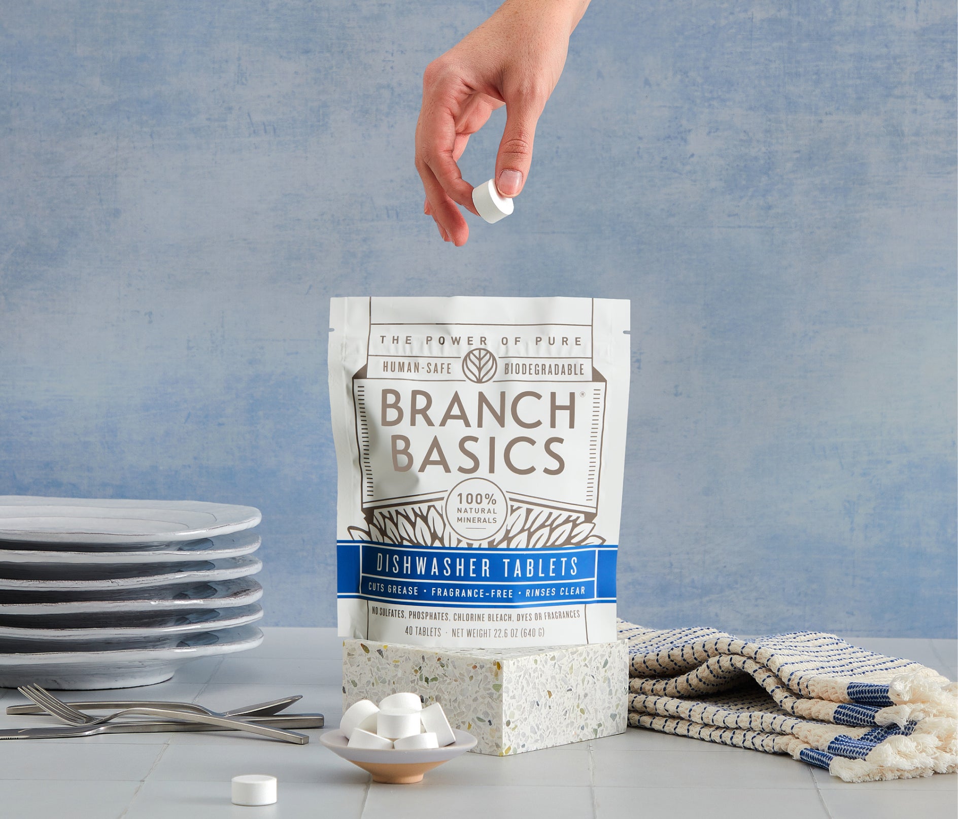 A standing bag of Dishwasher Tablets with a hand extracting a single Dishwasher Tablet from the bag. - View 3
