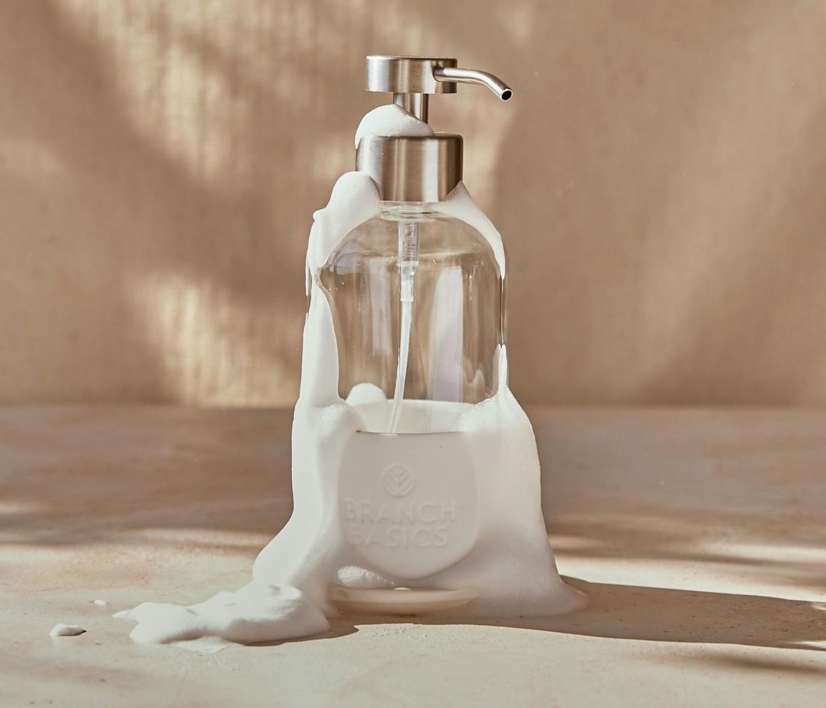 A single Glass Foaming Bottle with a Chrome pump covered in foaming bubbles against a neutral background. - View 9
