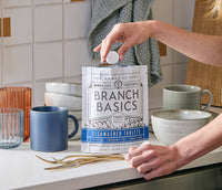 A standing bag of Dishwasher Tablets with a hand extracting a single Dishwasher Tablet from the bag. - Thumbnail View 7

