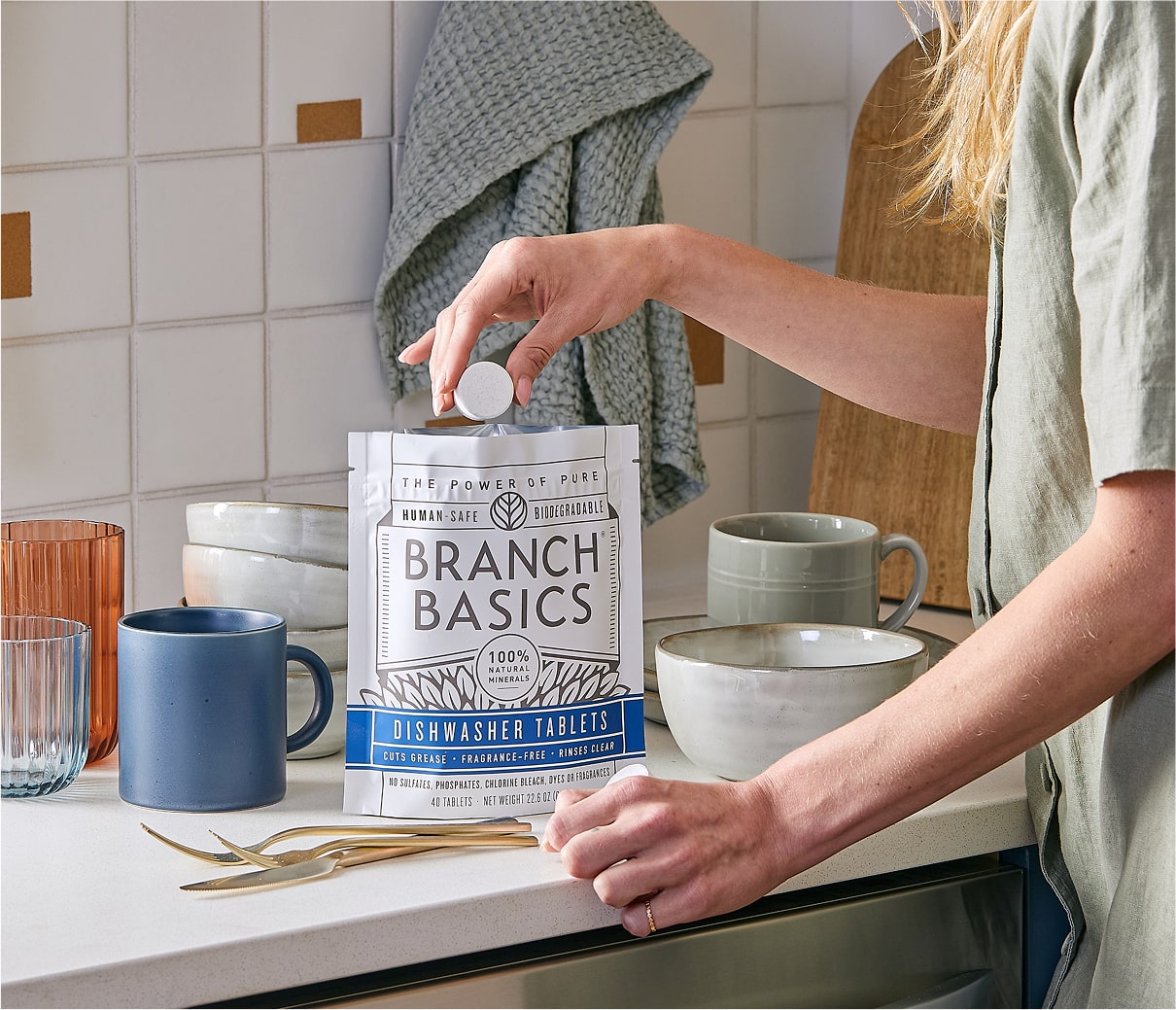 A standing bag of Dishwasher Tablets with a hand extracting a single Dishwasher Tablet from the bag. - View 7
