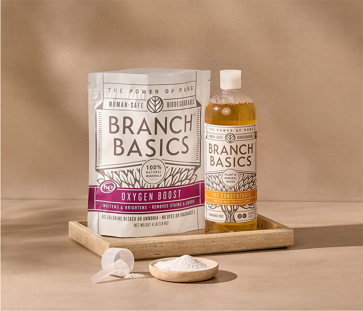 A bottle of Branch Basics Concentrate and a pouch of Oxygen Boost are displayed in a tray on a neutral surface and background. - View 1

