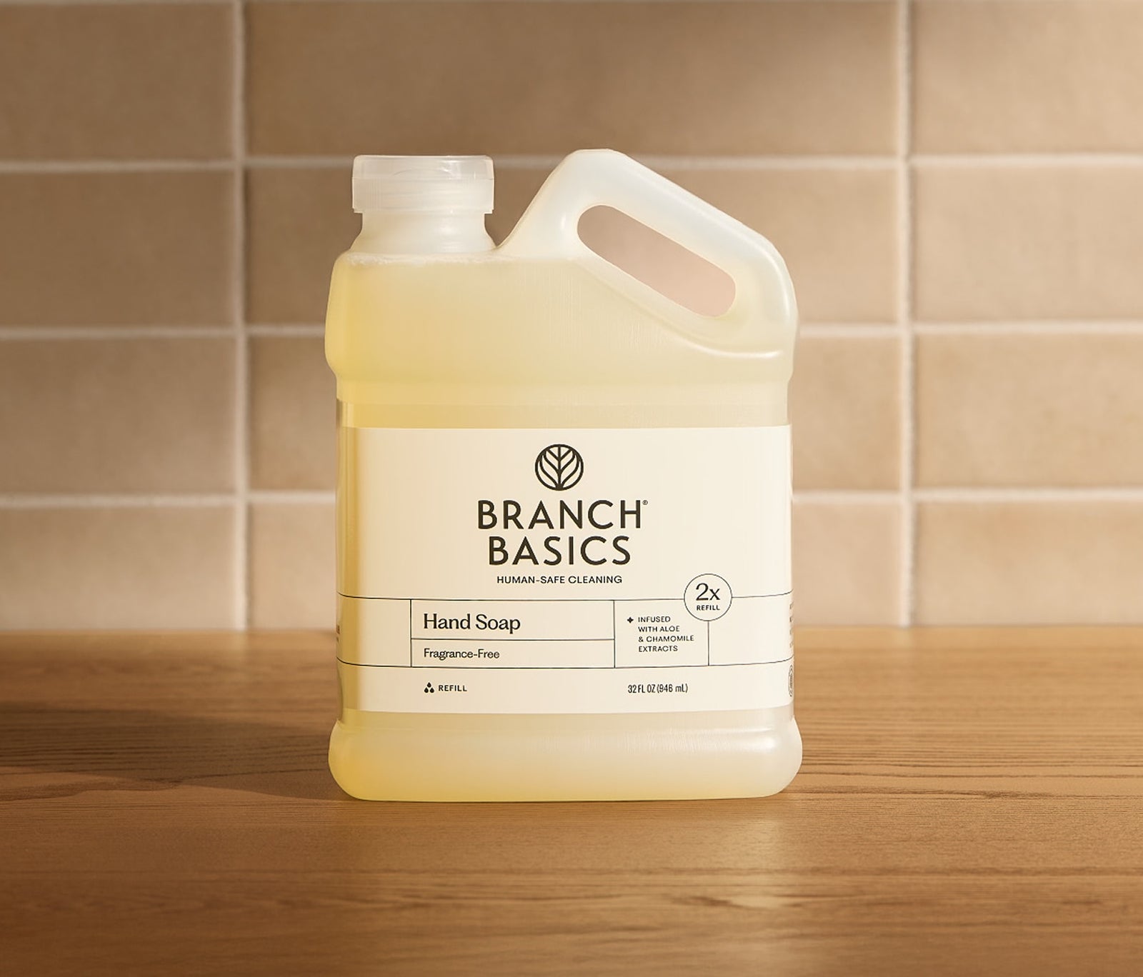 Branch Basics hand soap refill bottle on a wooden surface with a tiled wall background
