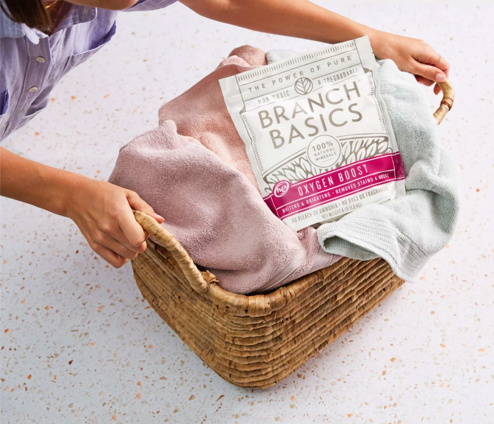 A full laundry basket with a pouch of Branch Basics Oxygen Boost sitting on top. - View 3

