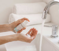 A person standing at a sink, using the mini Foaming Wash bottle to dispense foaming soap into their hands. - Thumbnail View 3
