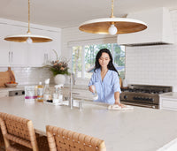 The Premium Starter Kit featuring Glass bottles displayed on a kitchen counter with a woman wiping the counter with a hand towel. - Thumbnail View 7
