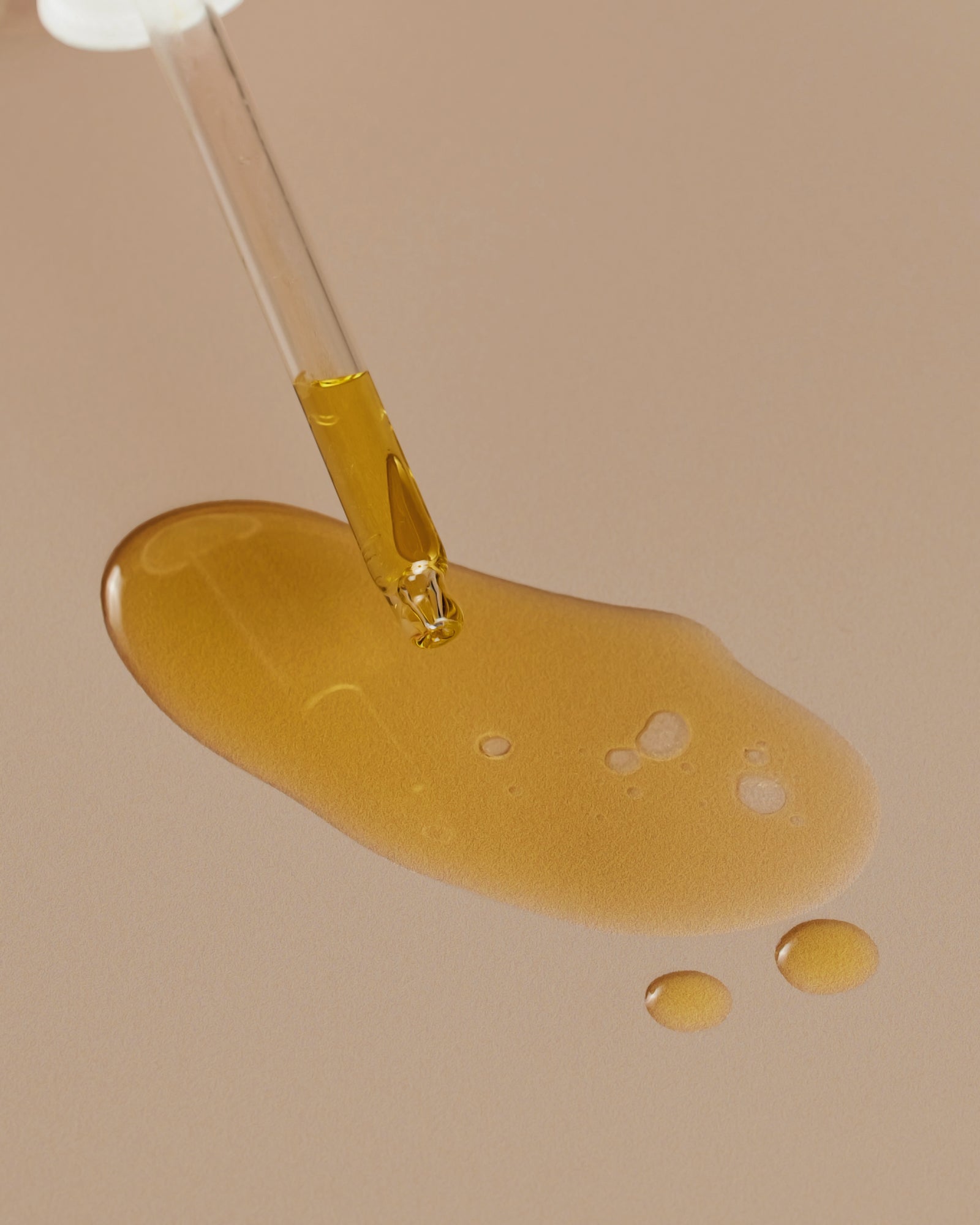A dropper of Meadowfoam Oil and a pool of Meadowfoam Oil positioned against a neutral background.
