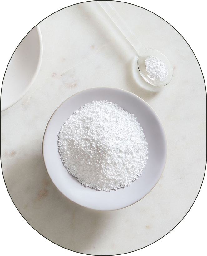 A bowl and small spoonful of Sodium Bicarbonate, positioned against a neutral background.
