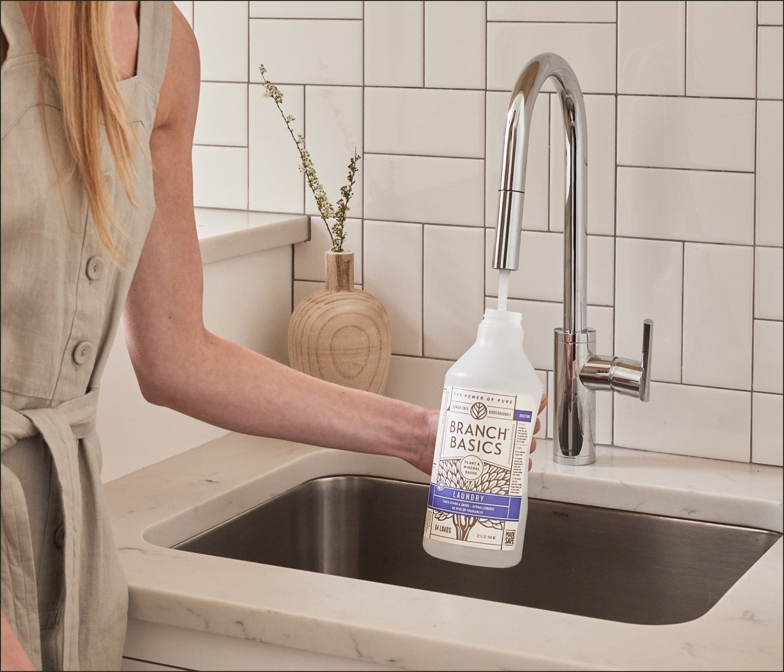 A person standing at a sink refilling a Plastic Laundry bottle. - View 3
